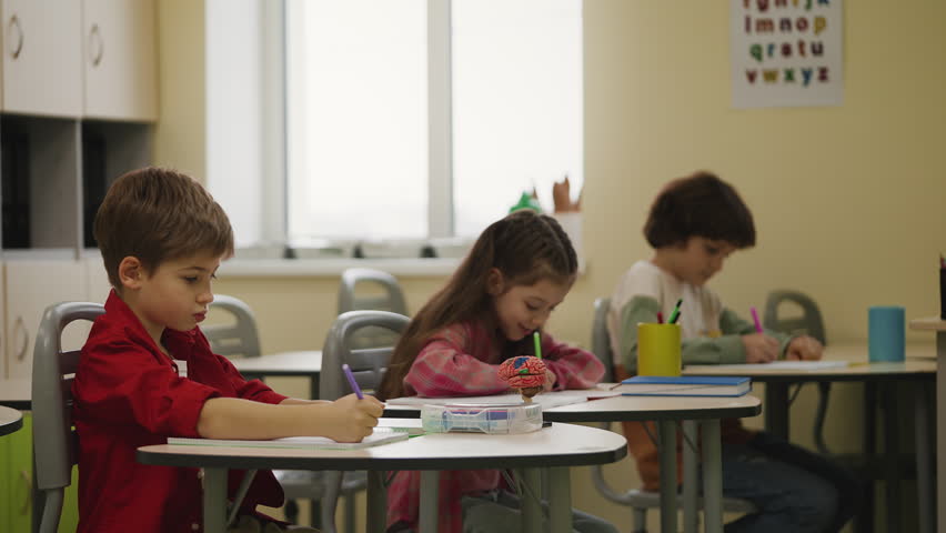 Children writing in notebooks during lesson in class, elementary education