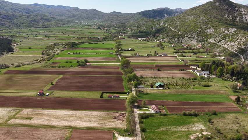 Aerial View of Farming Fields, Homes and Agricultural Land Under Mountains in Countryside
