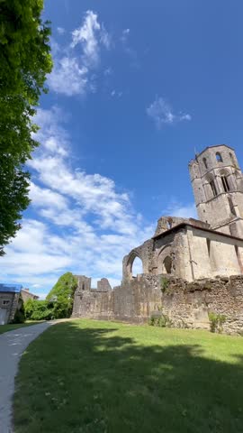 Visitors explore Abbaye de la Sauve-Majeur in Gironde, France under blue skies