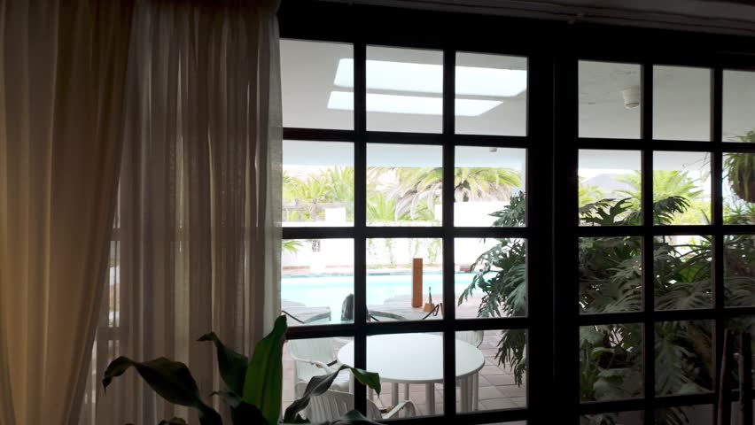 Looking through window with black frames at swimming pool and garden of César Manrique House Museum in Lanzarote, Spain