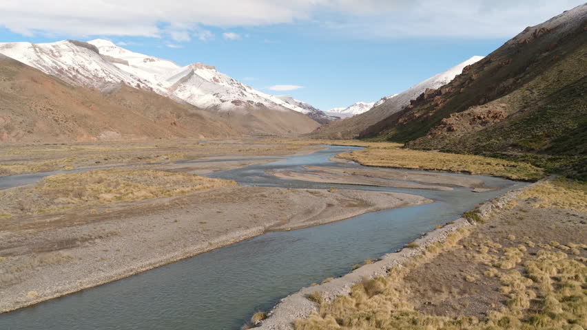 Cinematic drone flight above Río Grande valley with snowy Andes mountains in Mendoza, Argentina.