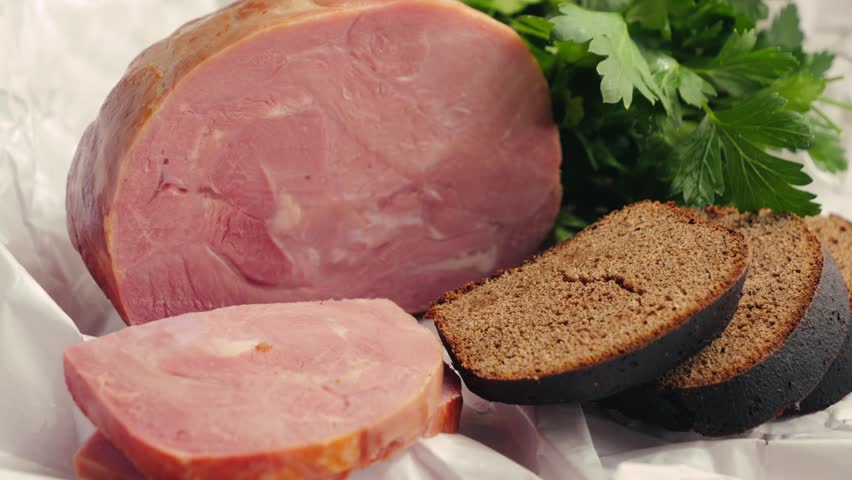 Close-up farm ham with rye bread and parsley on wooden cutting board. Snack and breakfast concept. High quality 4k footage