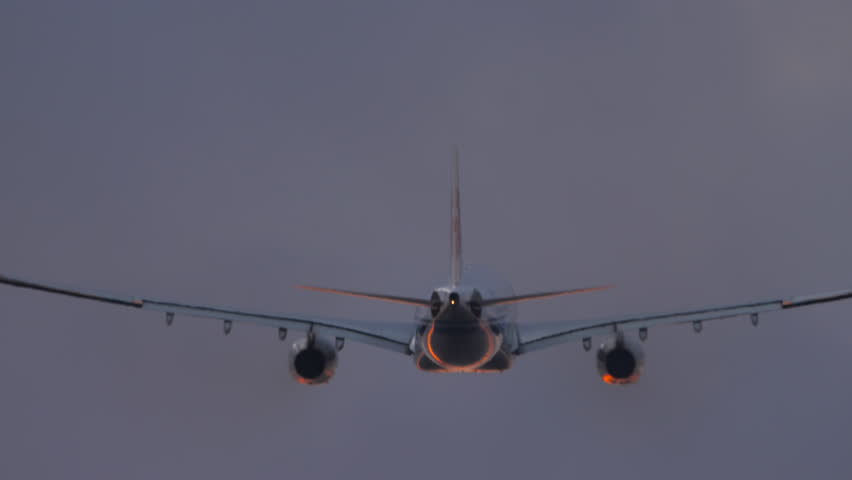 Large passenger airplane taking off and climbing into the beautiful sunset sky. Rear view of a commercial widebody jetliner flying away at dusk.