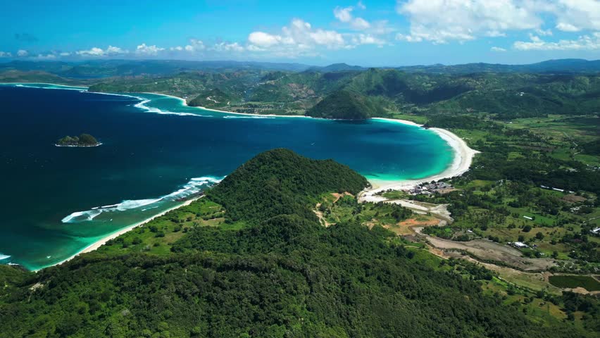 Stunning aerial view of Selong Belanak and Tomang-Omang beaches in Lombok, Indonesia showcases turquoise waters and lush green hills in cinematic 4K quality. Perfect for travel videos or destination