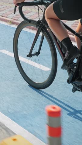 Close up of female legs riding on road bicycle on bike lane path. Vertical video