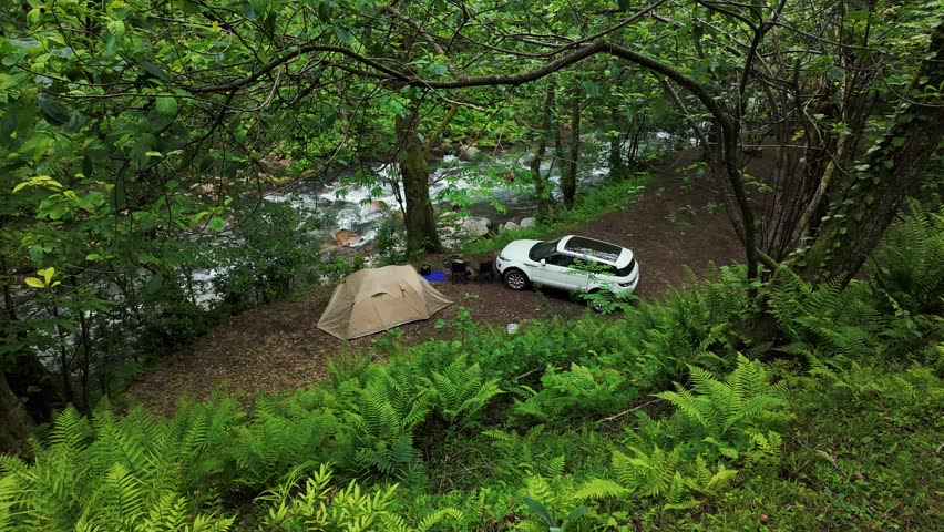 Forest Riverside Campsite with Tent and SUV. Peaceful Outdoor Camping Adventure.