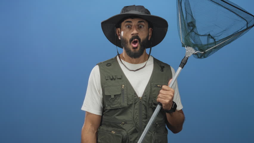 Man holding fishing net with hand gripping pole and open mouth gesture in studio; surprise curiosity.