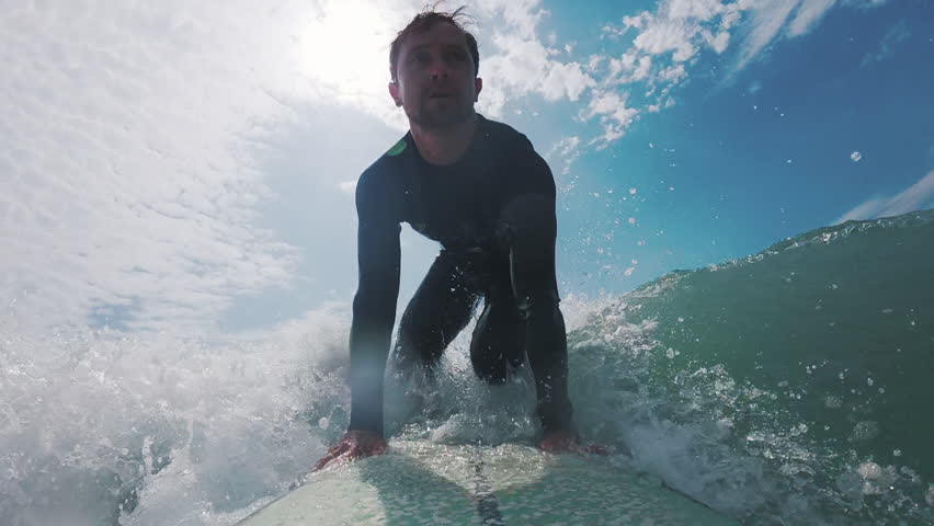 Man surfs the ocean wave. POV in water and underwater footage of the male surfer riding the wave