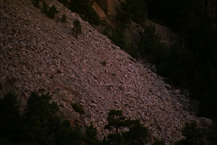 Tilt up rocky mountain side to Mount Rushmore in pink morning light in Keystone, South Dakota.