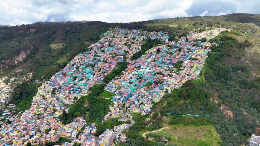 Vividly painted houses create a butterfly shape on the hillside, surrounded by lush greenery in Bogotá, Colombia.