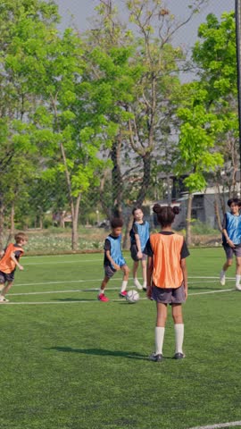 Two teams of kid football players competing during soccer game on sports field. Active young children running, practicing soccer skills and playing together in exciting teamwork competition activity.