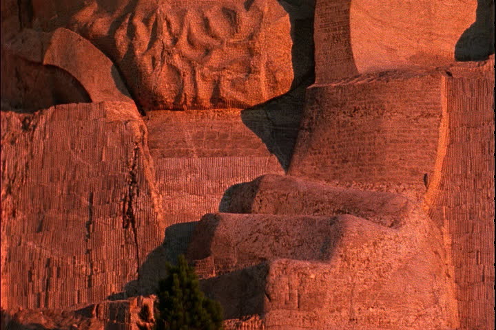 A flock of birds rush past camera as it tilts up to face of Abraham Lincoln in Keystone, South Dakota.