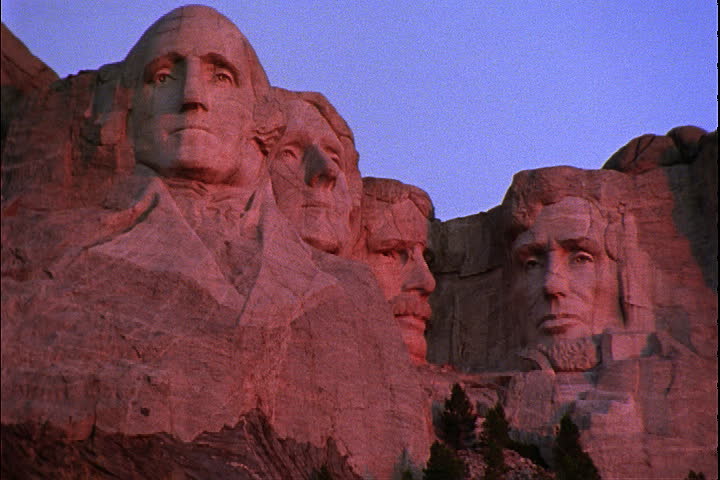 Zoom out from Mount Rushmore, tinted red in Keystone, South Dakota.