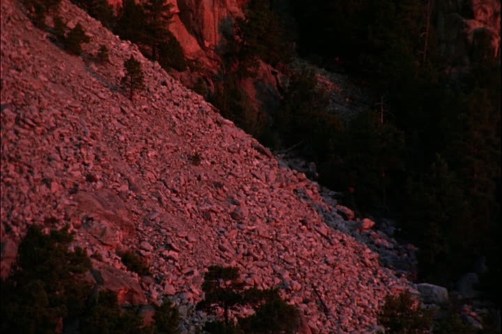 Tilt up rocky mountain side to Mount Rushmore with red tint in Keystone, South Dakota.