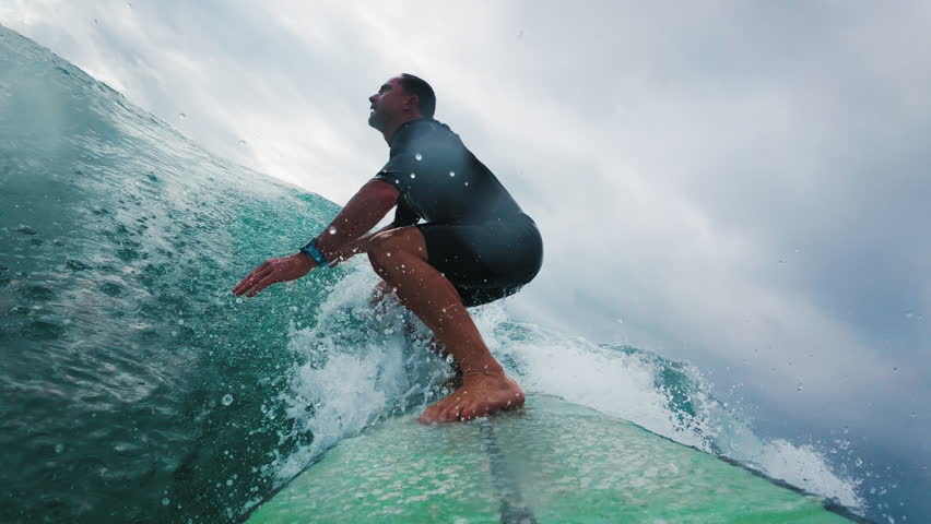 Surfer in wetsuit rides the wave in Atlantic Ocean. Surfboard camera view of the surf rider