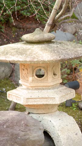 A slow pan reveals a stone toro lantern beside a small waterfall in Kanazawa