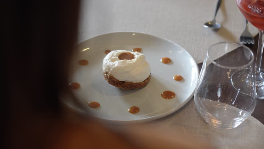 Gourmet dessert with whipped cream and caramel sauce on a white plate. Fine dining experience in a luxury restaurant.
