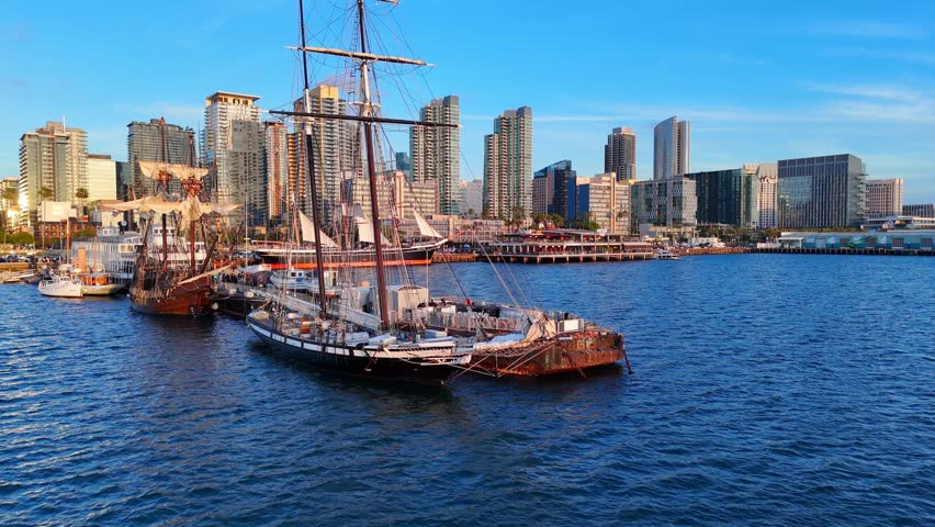 San Diego bay, CA, USA and city skyline, with historic sailing ships in aerial view on warm summer evening