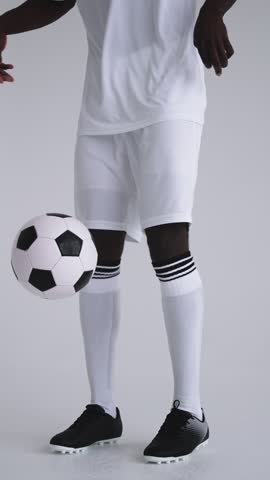 Close-up shots of a football player dressed in white sportswear controlling and juggling a classic black and white soccer ball during a training or practice session