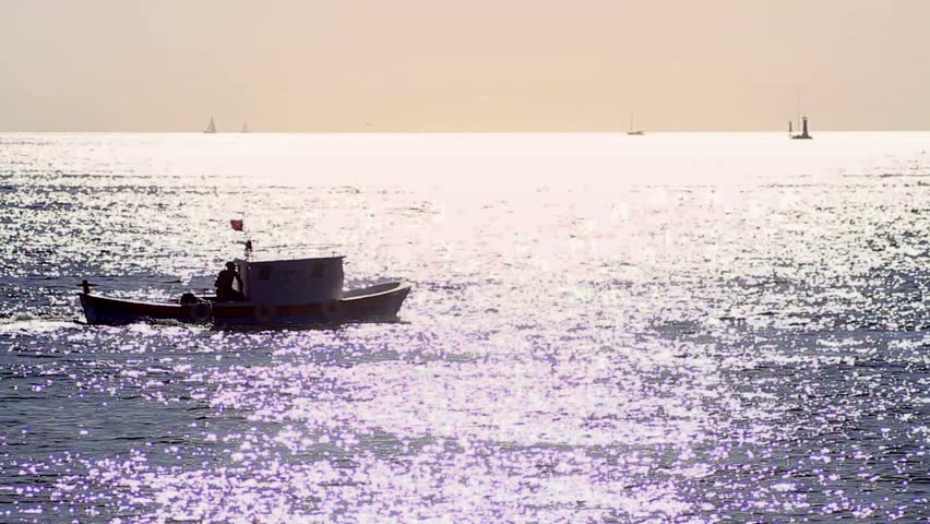 Bright, warm sea with a fishing boat at sunset