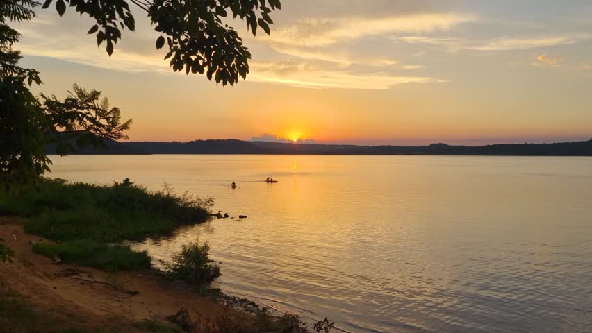 View over the Río Paraná near San Ignacio, Argentina, shortly after sunset, with calm waters reflecting the evening sky and Paraguay visible on the opposite riverbank in a peaceful tropical landscape