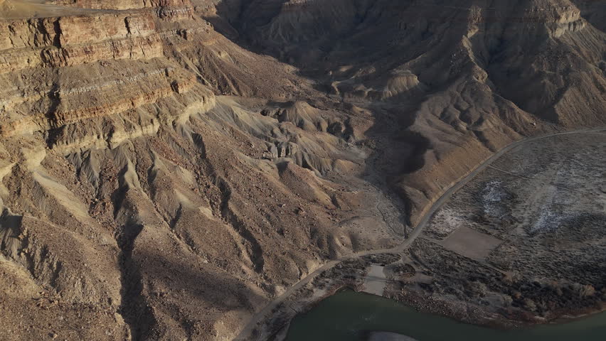 Aerial View of River Under Barren Sandstone Hills and Rock Formations, Green River Utah USA, Drone Shot