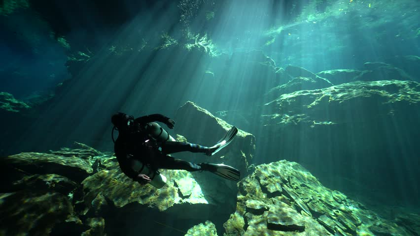 Scuba Diver Exploring Sunlit Underwater Cenote Cavern

Description: