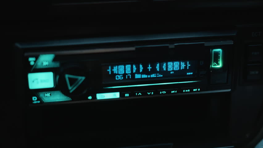 Car radio ambiance, Closeup of illuminated LCD showing tuning flicker and ambient mood, Serene cinematic scene featuring glowing car radio panel with flickering tuning numbers at night