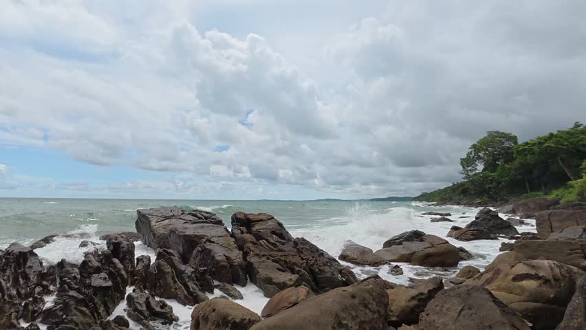 Waves crash against jagged coastal rocks.