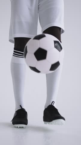 Young male soccer player in white uniform focusing on skillfully controlling the soccer ball with precision and balance during practice or a game