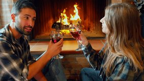 Romantic couple drinking wine and toasting by the fireplace. Happy young couple enjoying a romantic evening, toasting with glasses of red wine by a cozy fireplace - Powered by Shutterstock - Get 15% off with code: PIKWIZARD15