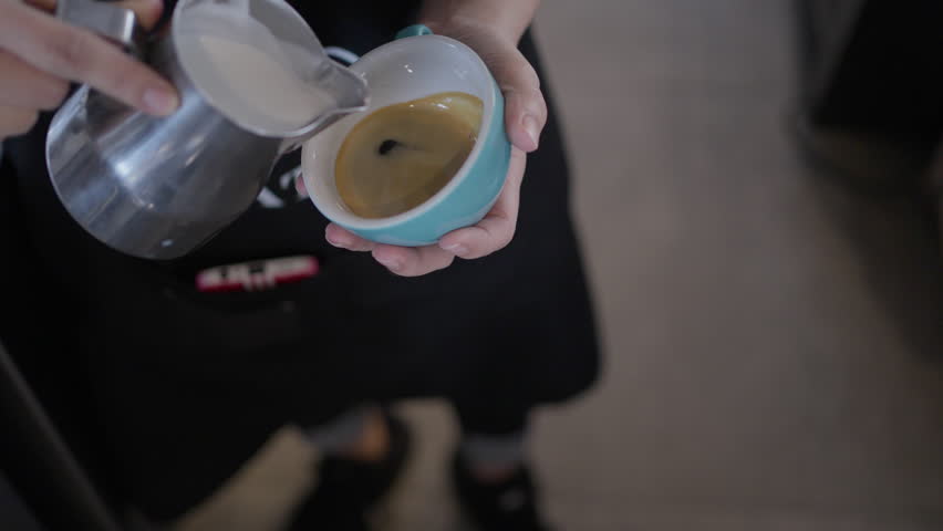 Latte art coffee cup barista milk pour close up warm beverage, barista pouring milk into coffee cup, close up hands making latte cafe with warm foam and stainless steel pitcher, espresso hot drink