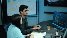 Two diverse software developers collaborate on coding at a modern office desk. A female programmer points at the computer screen while her male colleague types. Tech teamwork and problem solving. - Powered by Shutterstock - Get 15% off with code: PIKWIZARD15