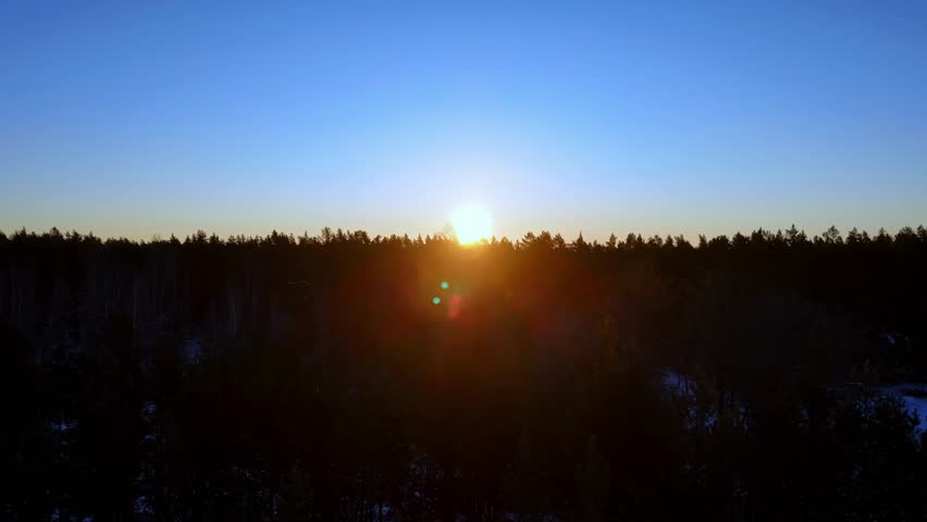 Golden Hour Over Winter Forest Aerial View Of Sun Rising Above Snowy Wilderness During Cold Morning In Northern Europe With Clear Blue Sky And Bright Sunlight Casting Warm Glow Across Frozen Horizon