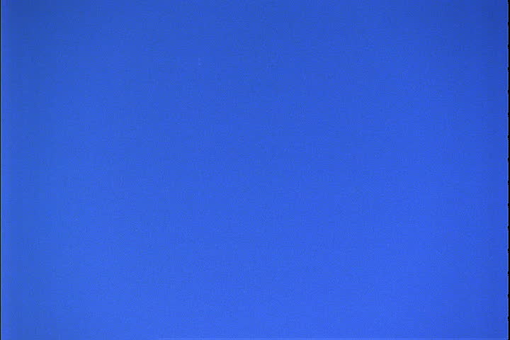 Camera tilts down from brilliant blue sky to Mount Rushmore, bathed in a red tint in Keystone, South Dakota.