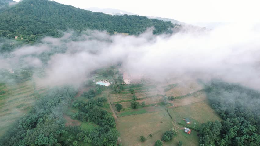 Mistshrouded countryside with tranquil accommodation. Peaceful rural lodge partially obscured by drifting fog
