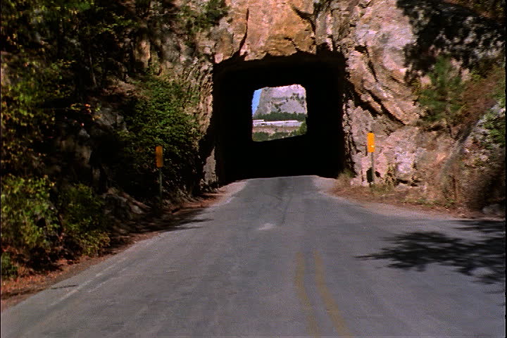 POV moving through dark tunnel cut through rock, and towards Mount Rushmore in Keystone, South Dakota.