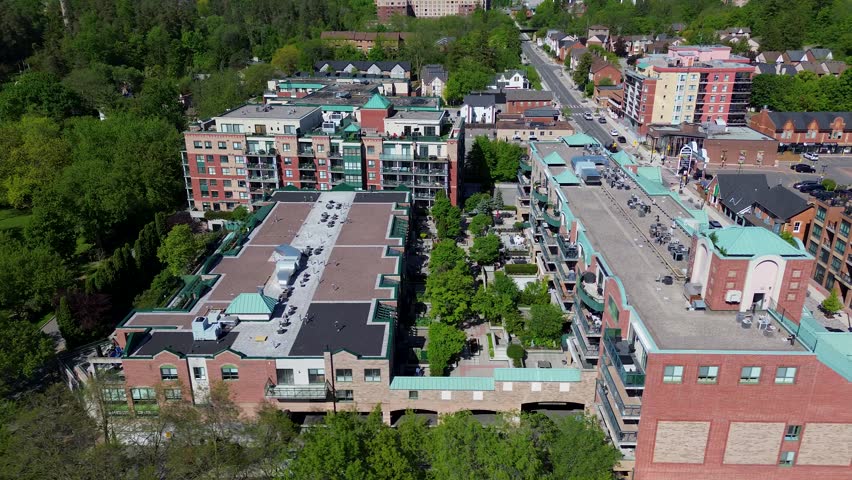 Drone view of residential buildings, condominiums, shopping plaza, and suburban neighborhood in Woodbridge, Vaughan during a sunny spring day with green trees and urban development visible. Vaughan, Canada - May 26, 2026.