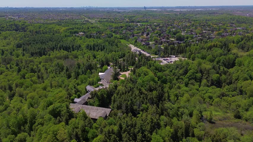 Drone view of the McMichael Canadian Art Collection surrounded by tall trees and green landscape during a sunny spring day in Vaughan Ontario. Vaughan, Canada - May 26, 2026.