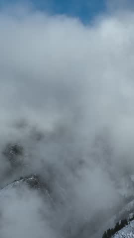 Aerial shot of the clouds and the rugged terrain of the Wasatch Mountains near Salt Lake City, Utah. Vertical Video.