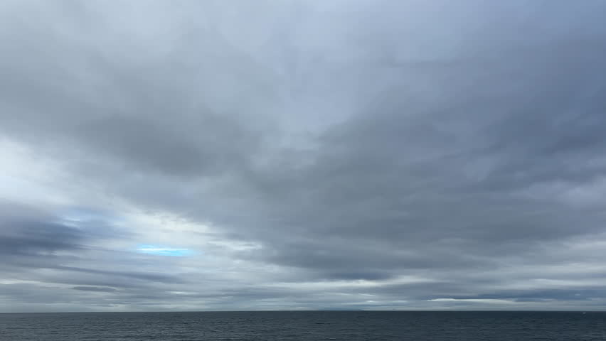 Glimpse of Blue Sky Breaking Through Heavy Storm Clouds Over the Sea