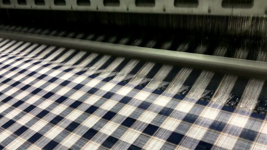 Weaving loom at a textile factory, closeup. industrial fabric production line Spinning factory, production of fabrics, thread of silk, linen, and synthetics