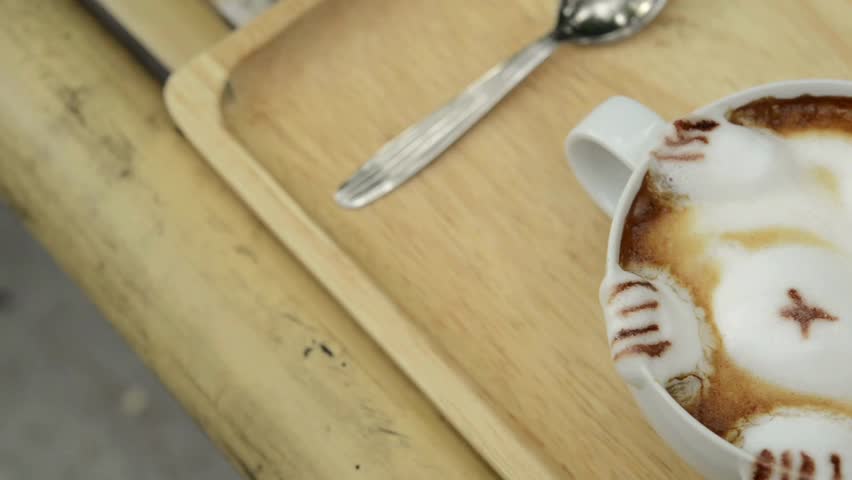 A cup of coffee with cute animal shape latte art, perfect for breakfast time. Hot Mocha coffee with cute latte art made by milk foam on top of a cup.