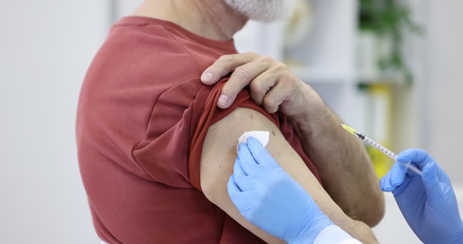 Nurse in medical gloves vaccinating man in hospital, closeup