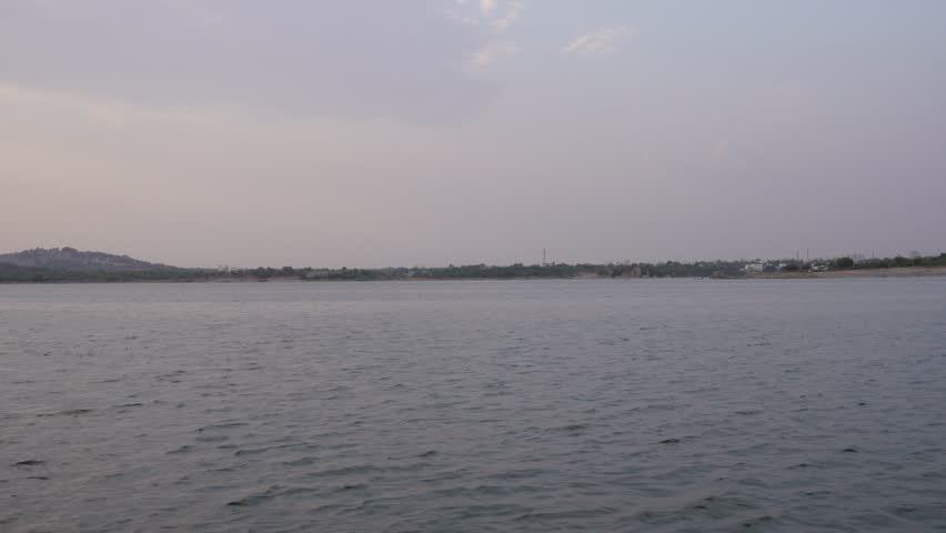 Wide lake landscape under a muted evening sky with distant shoreline and calm water.