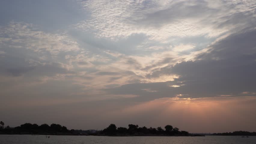 Dramatic evening sky above a tranquil lake with textured clouds and soft sunset colors.