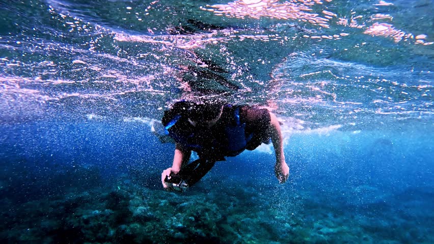 People snorkeling in clear tropical ocean water near Nusa Penida, Bali, enjoying marine life and underwater adventure.