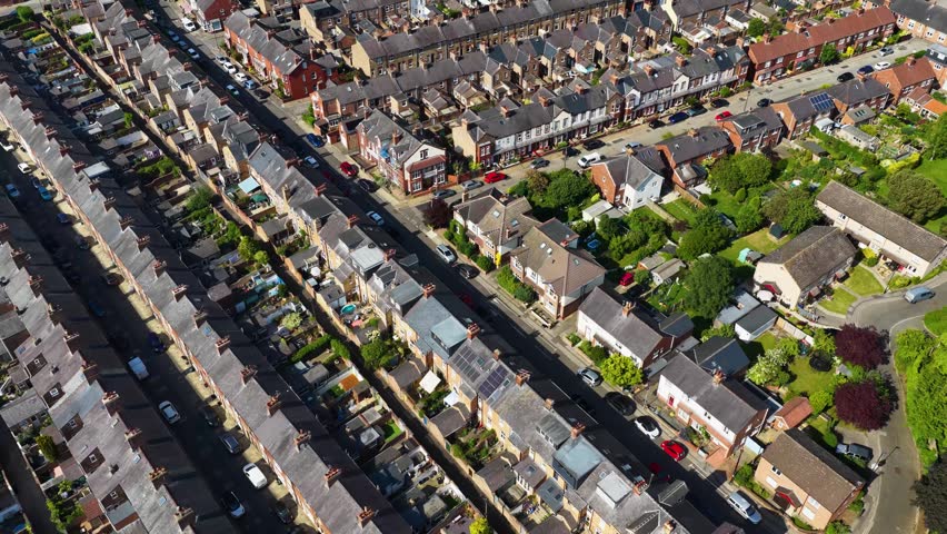 Aerial drone footage of rows of  terraced housing and suburban streets in the city of York North Yorkshire England showing brick homes gardens roads and residential urban development in the summer