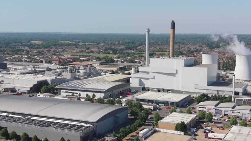 Aerial perspective shows a vast industrial complex featuring a large data center, multiple cooling towers, and tall smokestacks emitting steam.