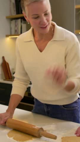 Vertical video: Rolling mom with pin in kitchen daughter joining cutting stars for cookies in knits. Dough, women, baking, modern, collaboration, holiday, vertical video